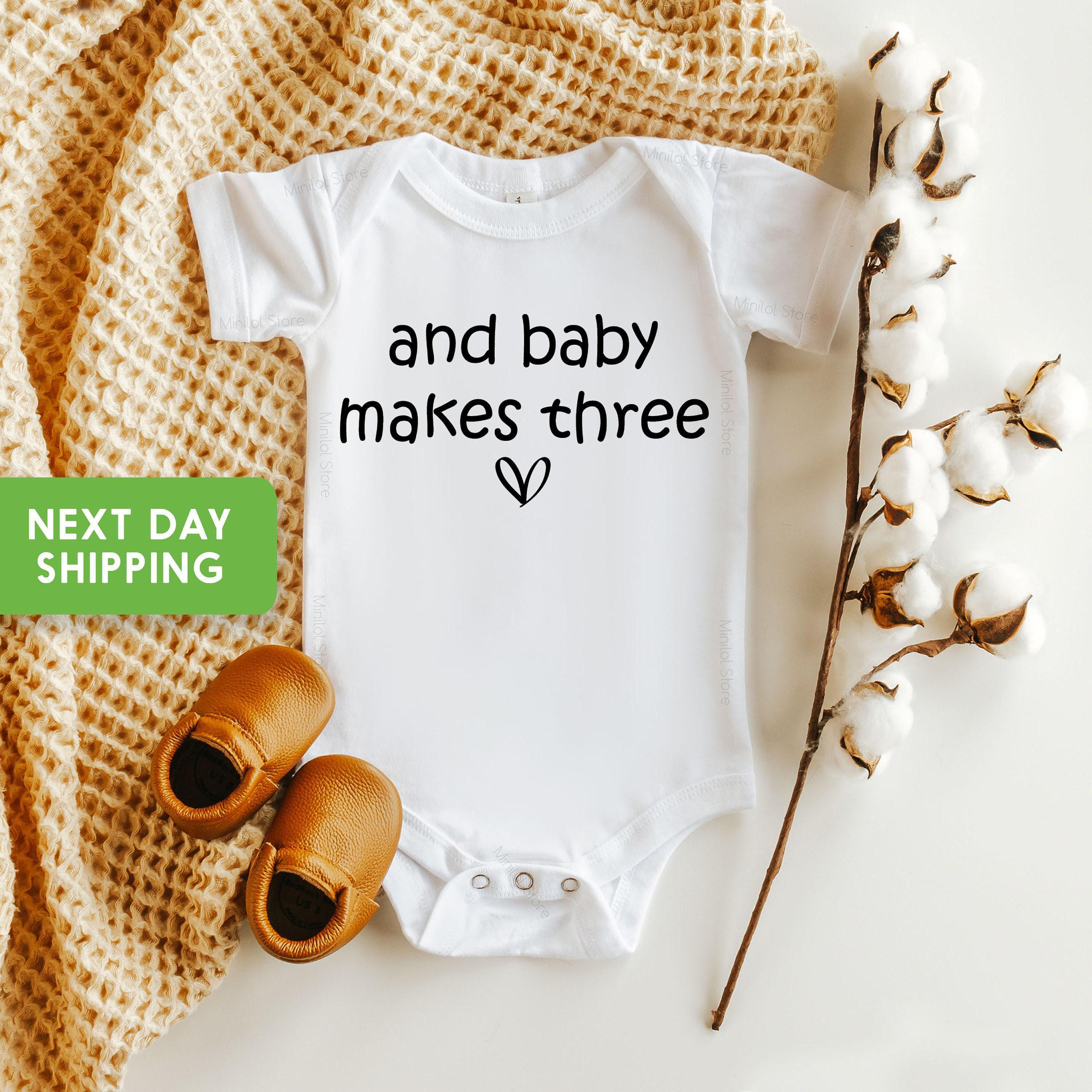 Main pregnancy announcement product mockup for Baby Makes Three Pregnancy Announcement Baby Announcement Onesie®